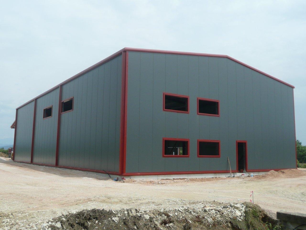 Finished steel warehouse with gray insulated panels and red trim in Arta