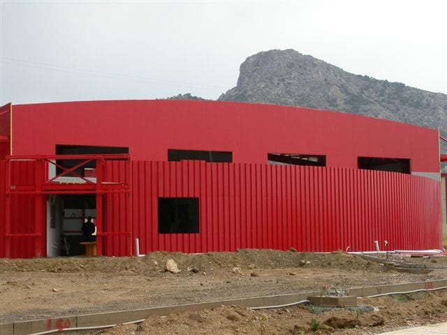 Curved front facade with red metal sheet cladding at the vehicle inspection center in Aspropyrgos