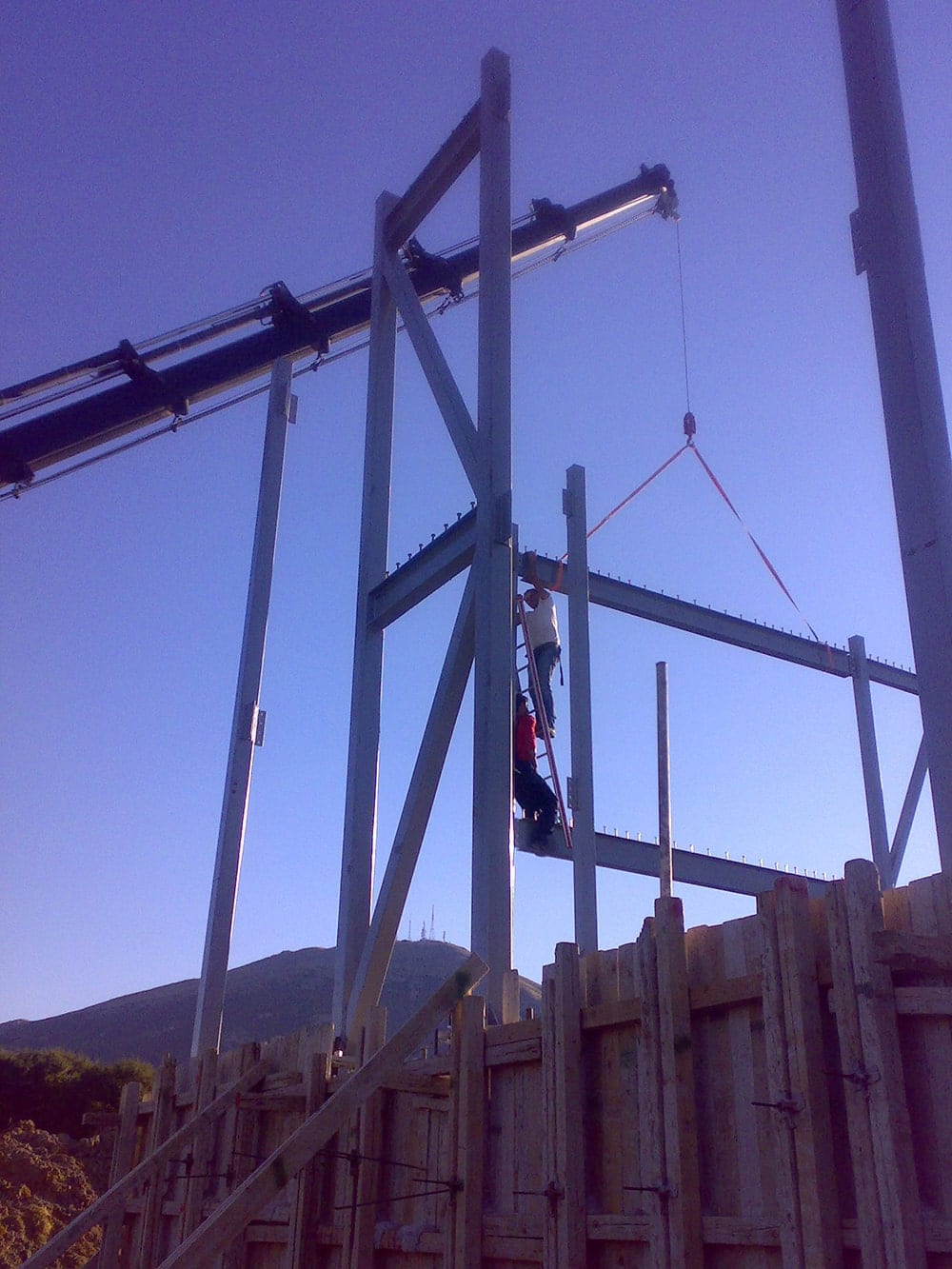 Lifting a beam with a crane during erection of the house frame in Episkopiko, Ioannina