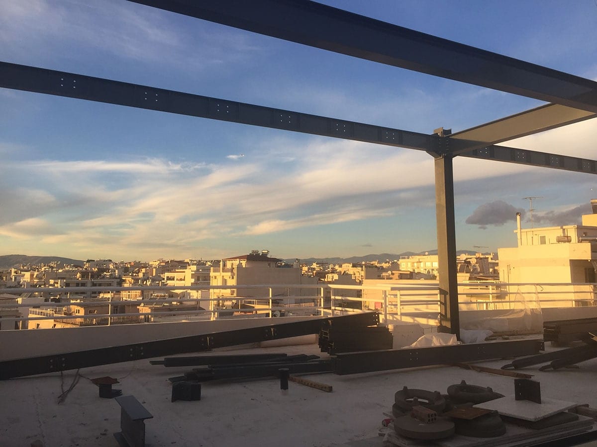 Steel frame of a vertical addition on a rooftop overlooking the city in Alimos