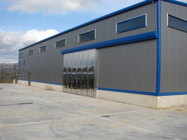 Steel building with gray panels, blue trim and a stainless steel door in Karystos