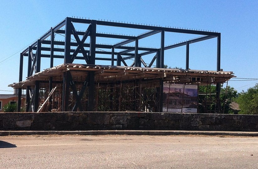 The steel and concrete structure of the store and house in Razata, Kefalonia, seen from the road