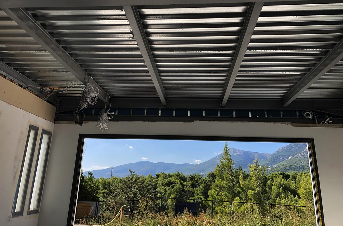 Floor structure with steel beams and a large opening with a view at the maisonette in Varympompi
