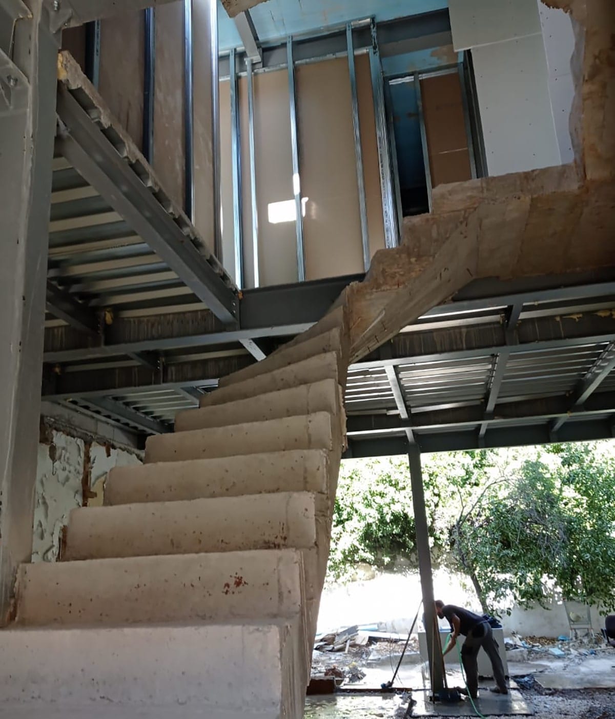 Interior with the steel slab supports and the staircase at the two-story building in Ano Petralona