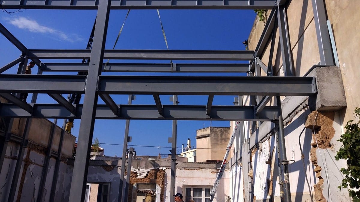Steel frame next to existing masonry at the two-story building in Ano Petralona