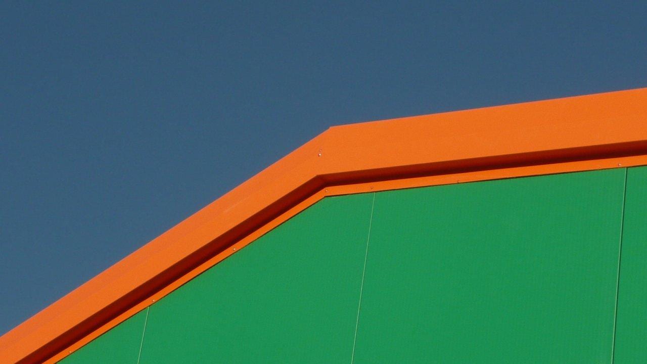 Gable detail with green panels and orange trim at the rabbit farm in Thiva