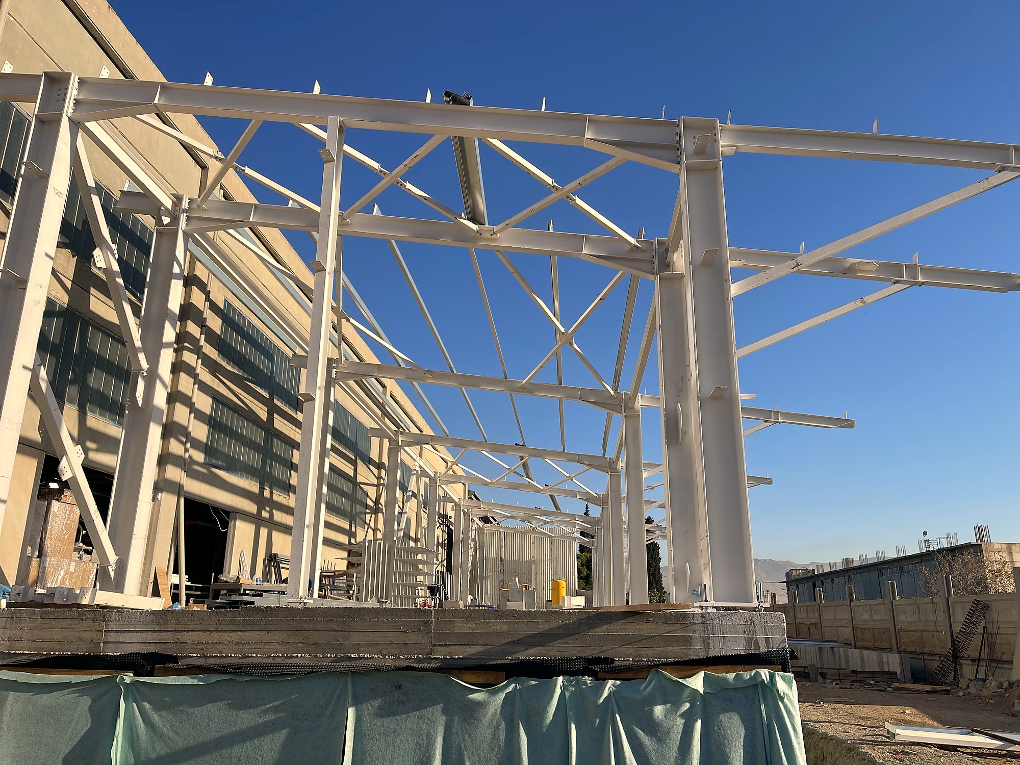 Steel frames with cantilevered lattice trusses during erection, industrial building in Aspropyrgos, Attica