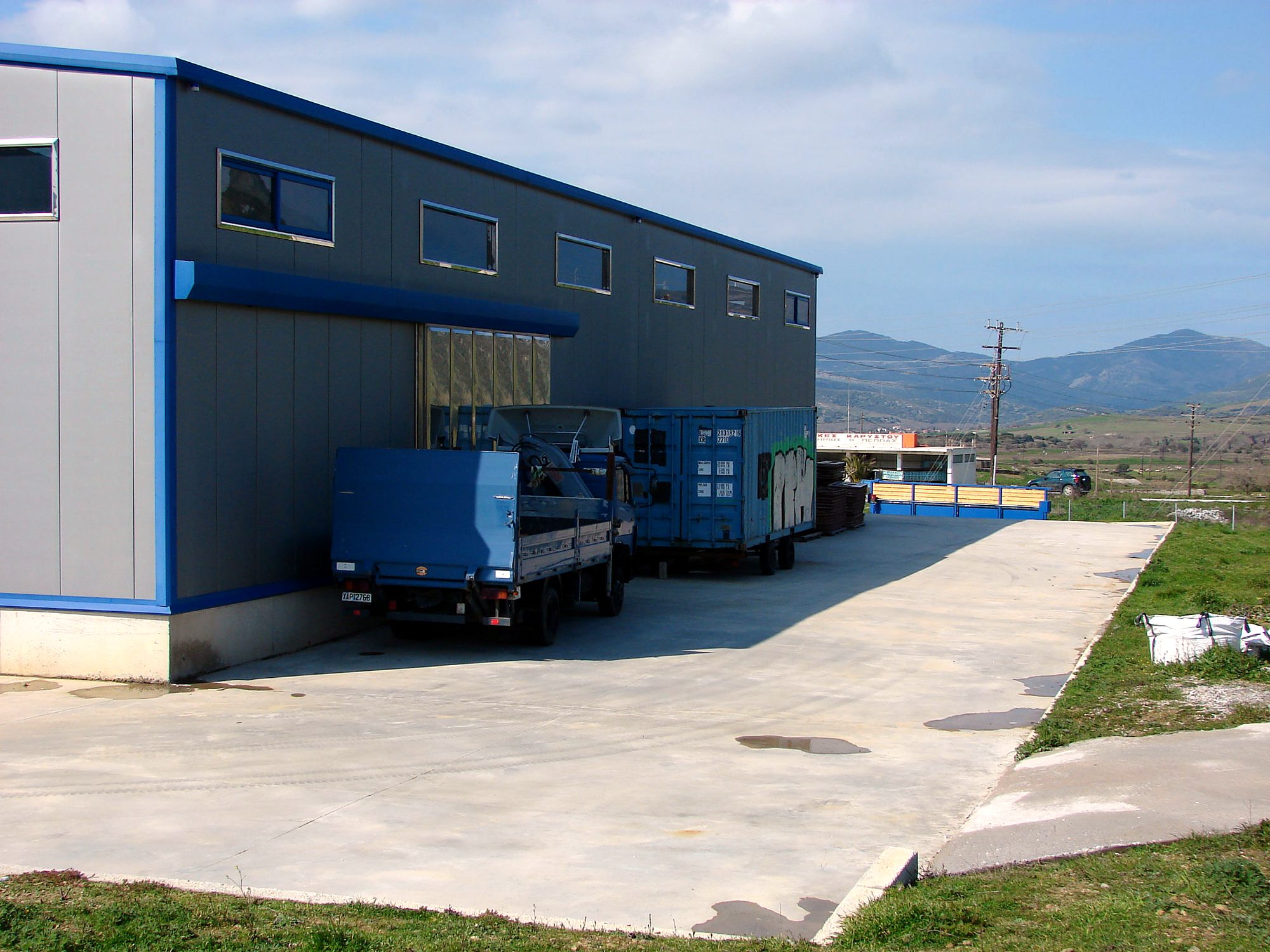 Side view of the steel building with a canopy and paved yard, Karystos, Evia