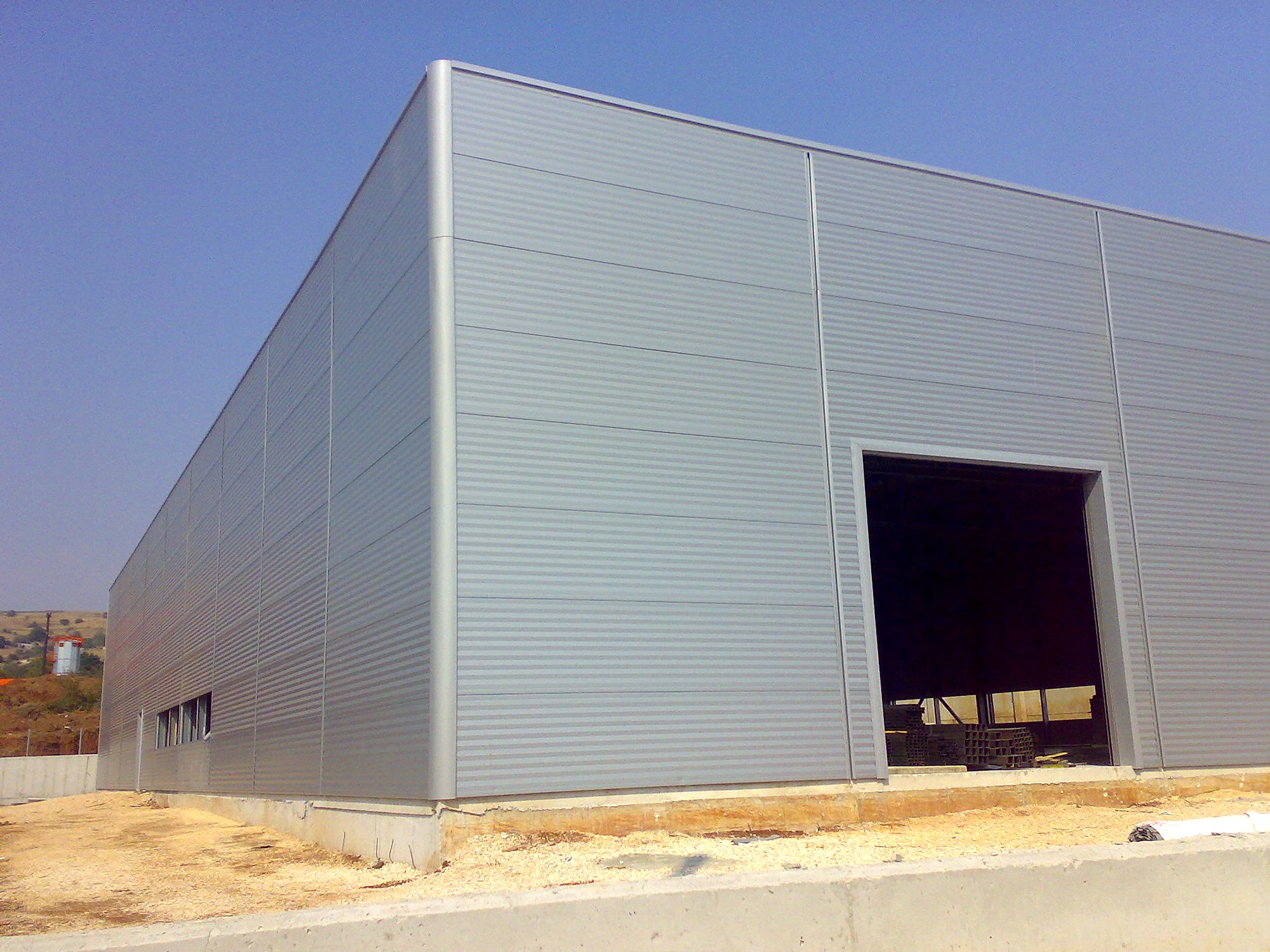 Corner of a steel light-industrial building with horizontal insulated wall panels, Ioannina industrial zone