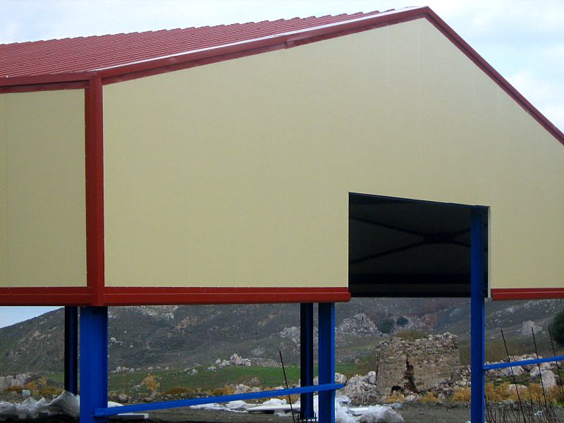 Λεπτομέρεια αετώματος με πάνελ και άνοιγμα εισόδου σε μεταλλικό βουστάσιο στην Κω