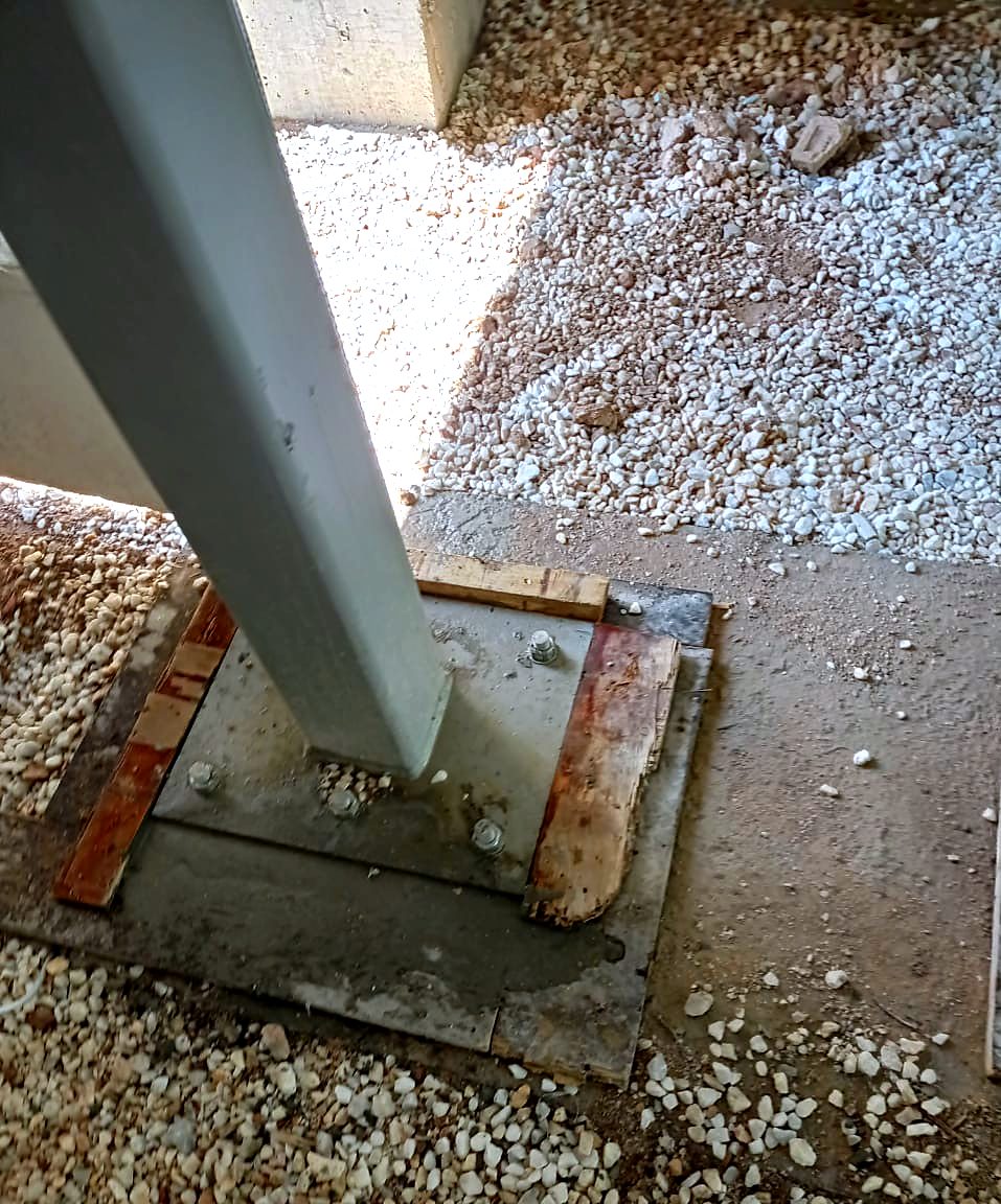 Base plate of an inclined steel column with anchor bolts, steel and concrete building in Petralona