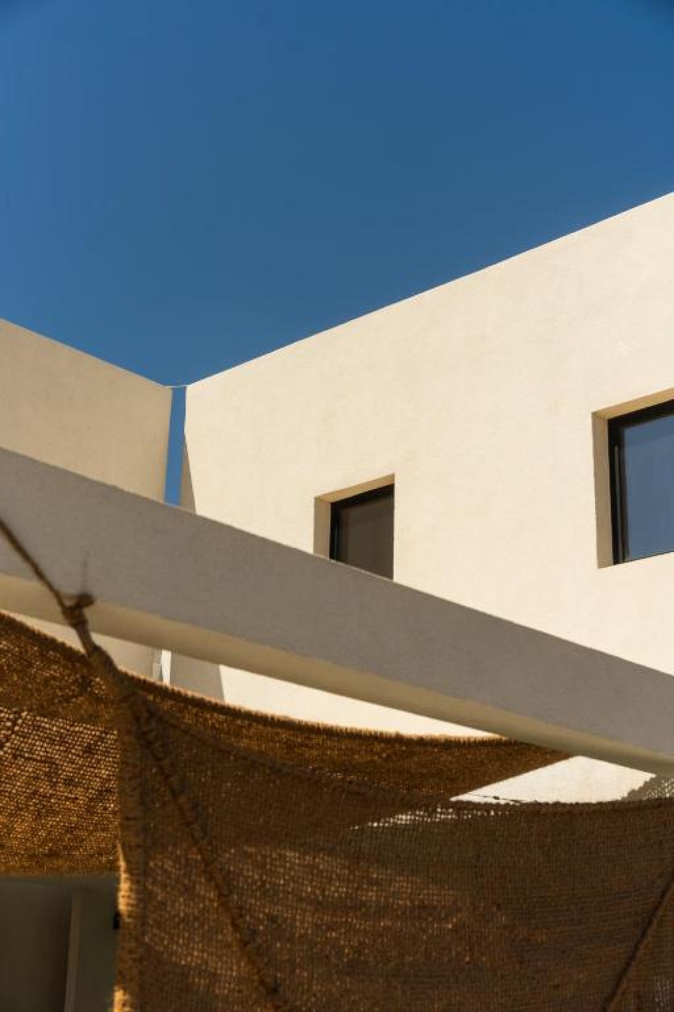 Exterior view of the rental rooms on Skyros with white volumes and a shade structure